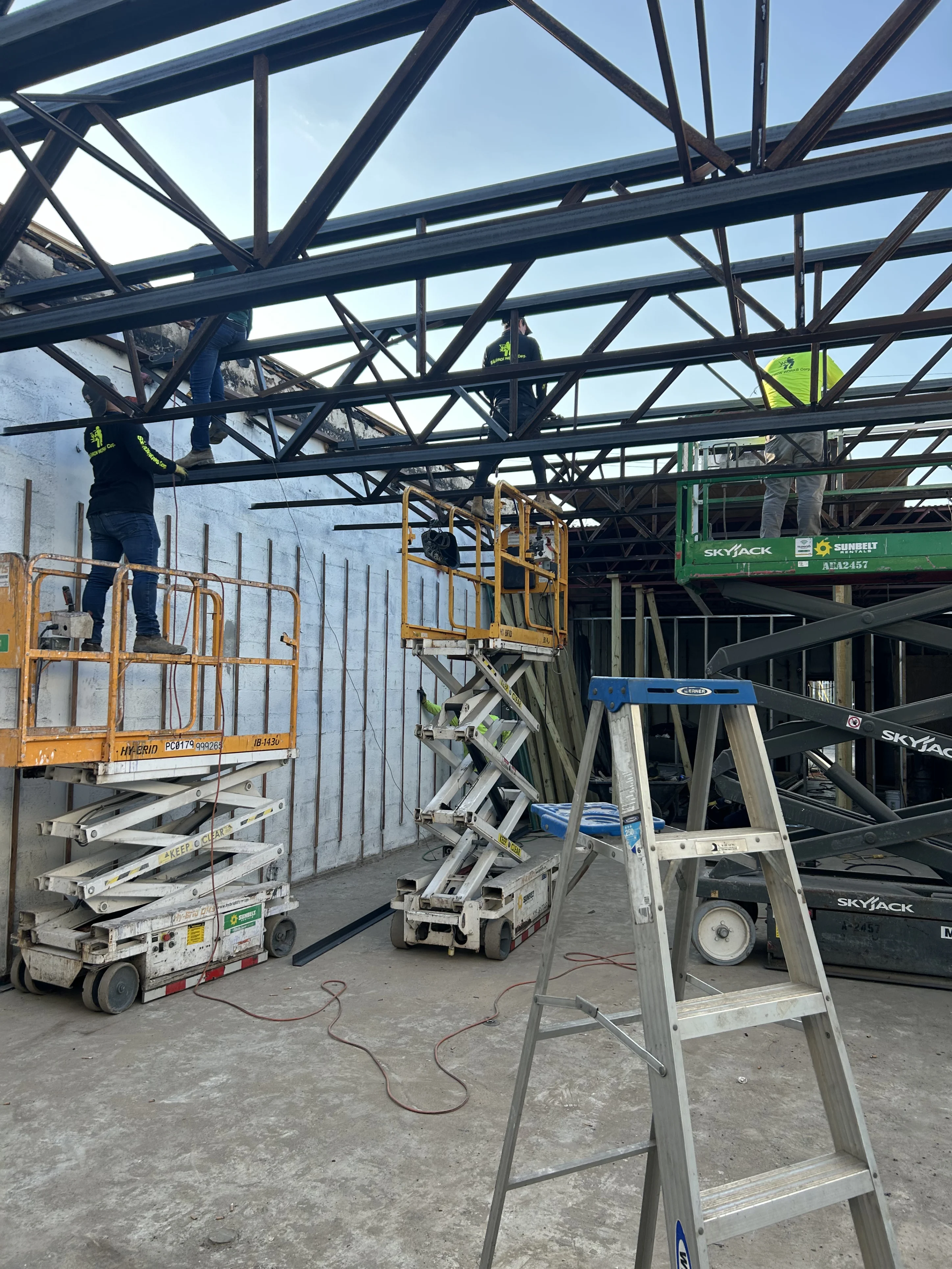 Construction A man standing on a scissor lift in the middle of a building.